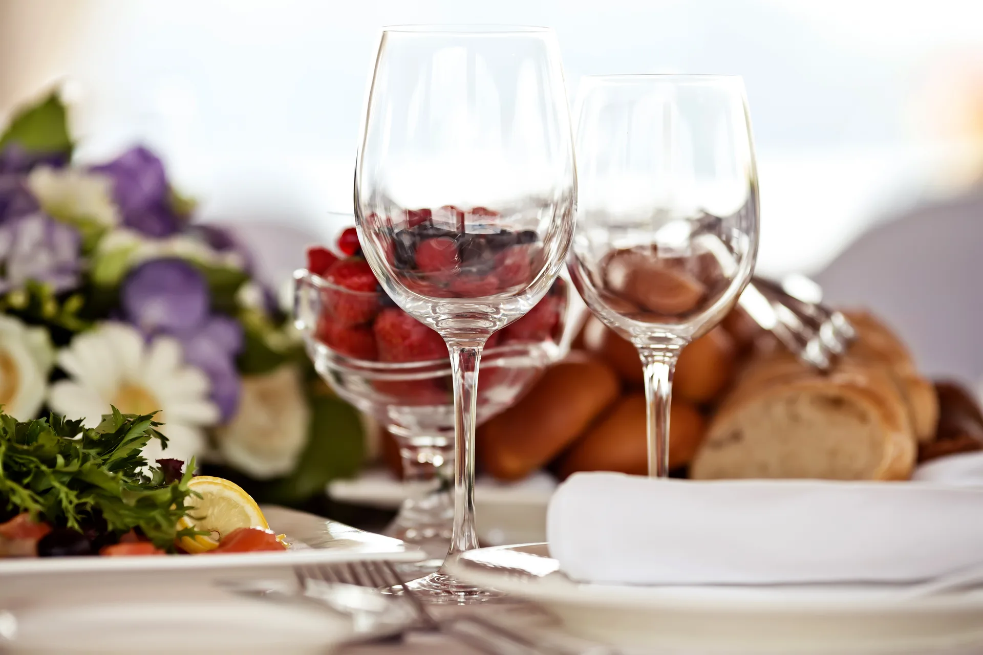 Gedeckter Tisch mit Weingläsern, Brot und Blumenschmuck