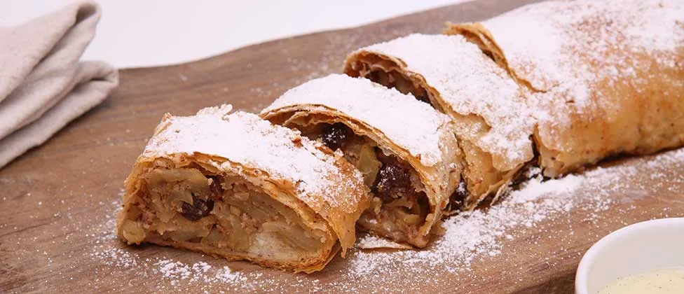 Apfelstrudel mit Puderzucker auf einem Holzbrett
